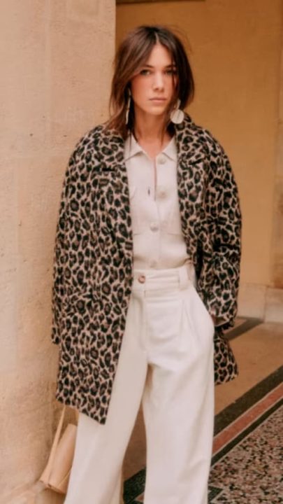 Une femme portant un manteau mi long en motif léopard se la marque Sezane
