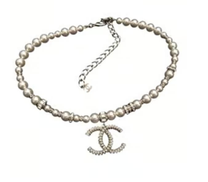 Un collier en perles ras de cou avec le sigle Chanel en argent.