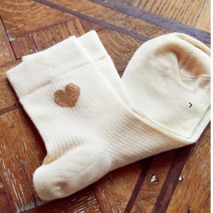 Petite paire de chaussettes blanches avec un petit coeur doré sur la cheville de chez Sezane