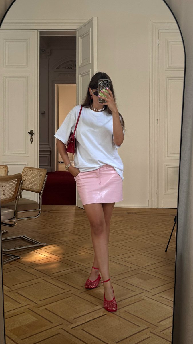 tenue femme bureau : mini jupe en cuir rose avec t-shirt blanc oversize et accessoires rouges