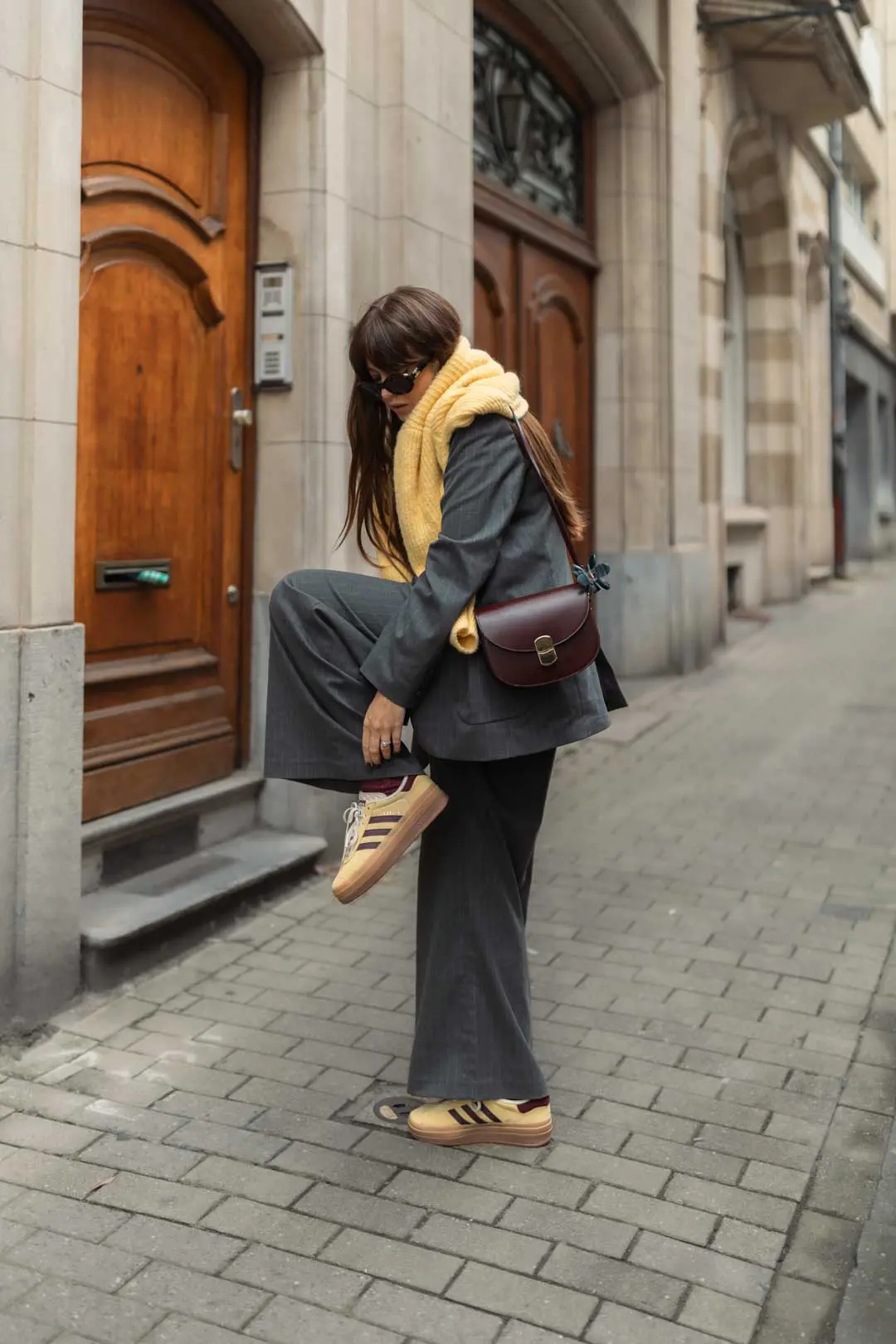 tenue automne femme : tailleur gris avec pull et baskets jaunes et sac bordeaux